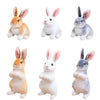 A collection of four lifelike plush rabbit stuffed animals in various colors and poses.