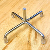 A chrome miniature doll seat car vent decoration shaped like a star or cross.