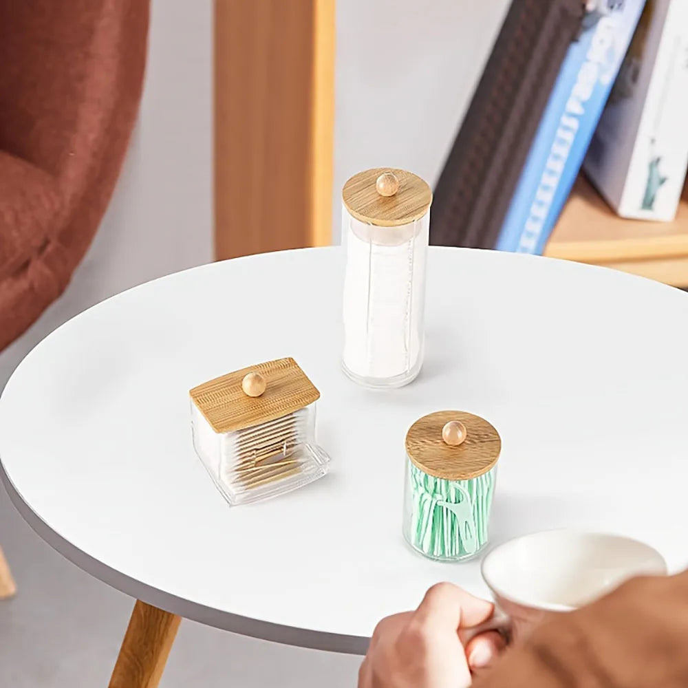 A set of three wooden and glass cotton swabs and a bathroom organizer displayed on a white table.