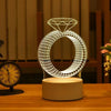 A glowing wireframe diamond ring pendant light displayed on a wooden surface.
