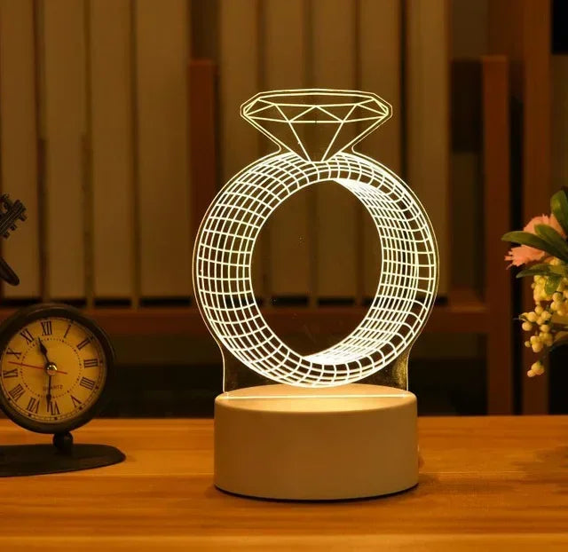 A glowing wireframe diamond ring pendant light displayed on a wooden surface.