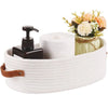 A white woven cotton rope storage basket holding a roll of toilet paper and a floral arrangement.