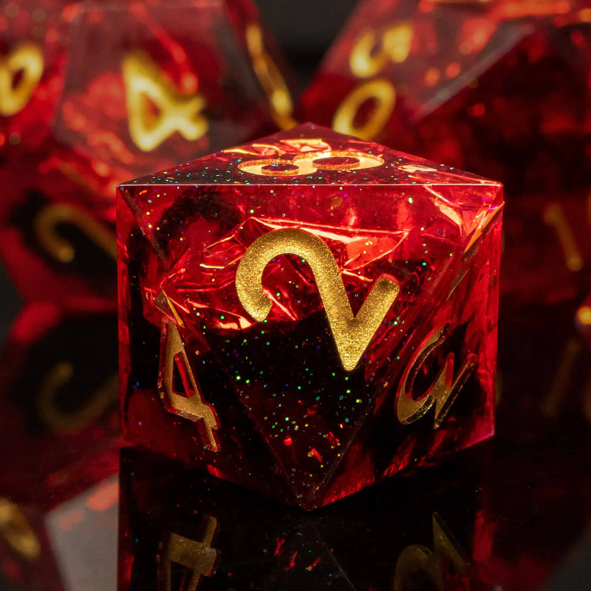A close-up of a red resin polyhedral die with gold numbers, reflecting on a dark surface.