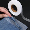 A hand is applying no-sew iron-on hem tape to the edge of a denim garment.