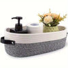 A woven cotton rope storage basket holding a roll of toilet paper and a small floral arrangement.