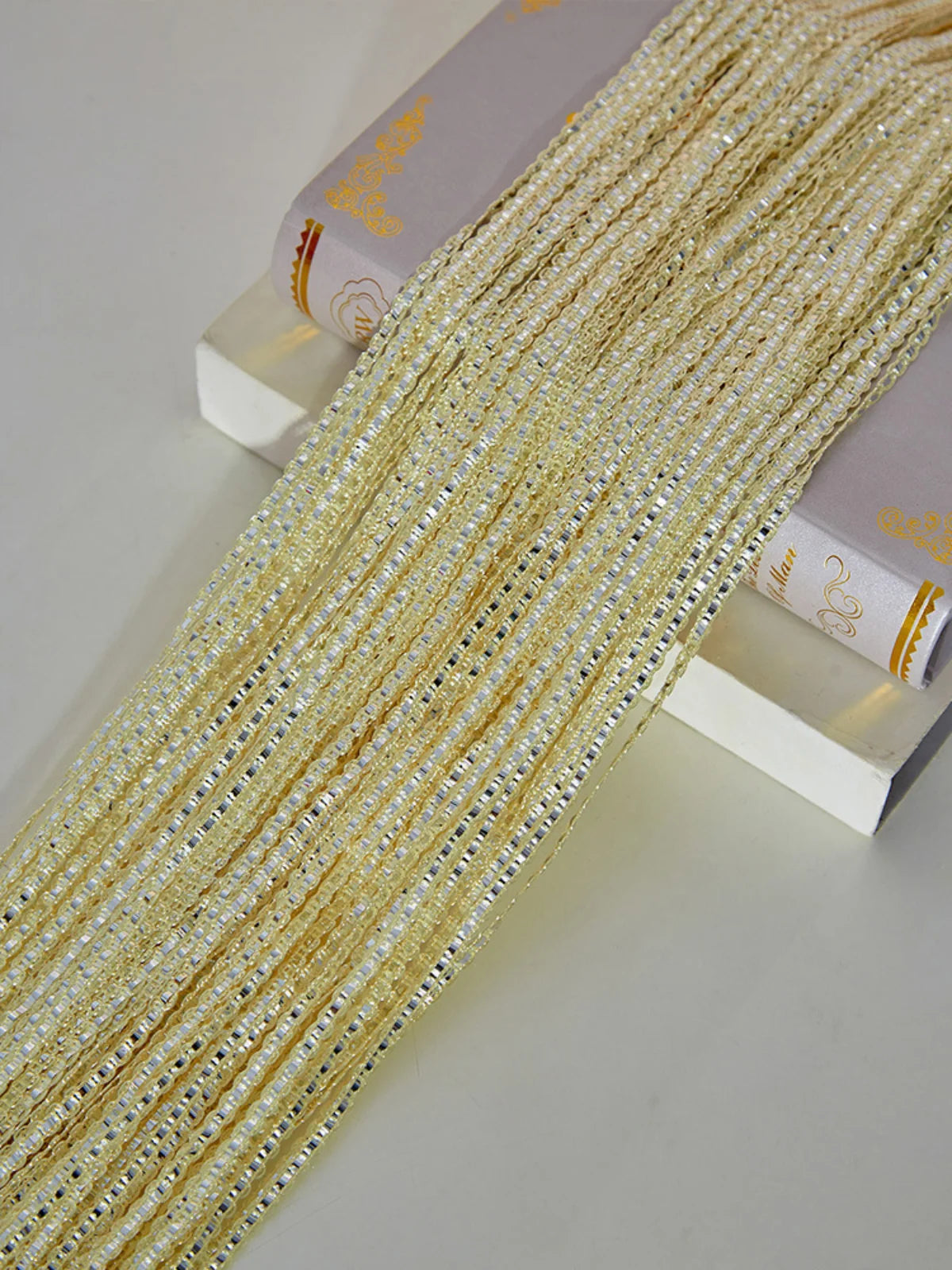 Gold beaded tassel string curtain displayed next to a book.