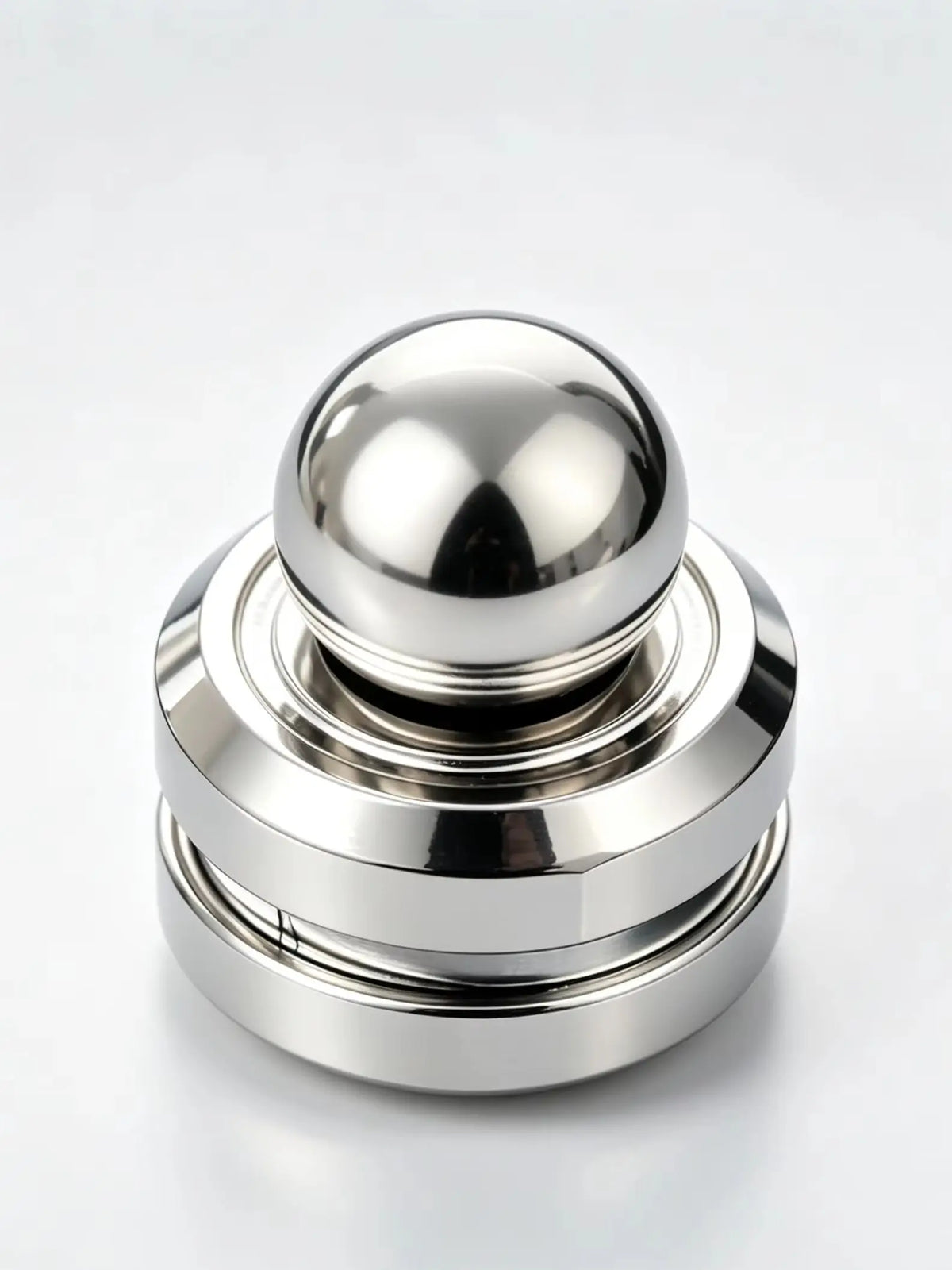 A polished silver kinetic metal desk spinner with a smooth spherical top and stacked rings.