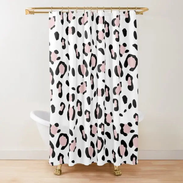 A white shower curtain featuring a black and pink leopard print pattern hanging from a gold rod.