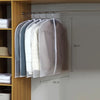 A display of transparent zippered garment bags hanging on a rod against a light gray wall.
