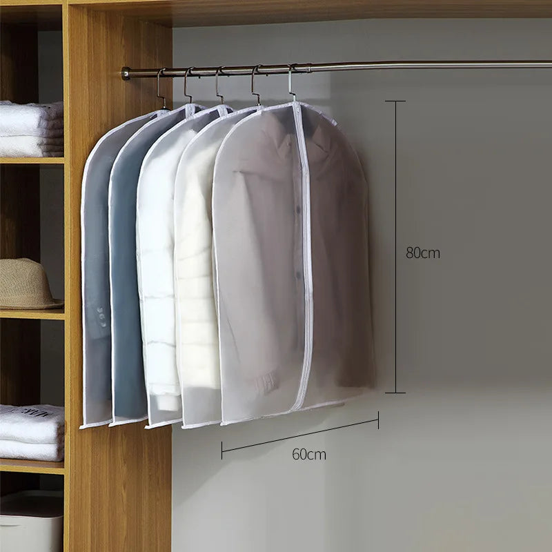 A display of transparent zippered garment bags hanging on a rod against a light gray wall.