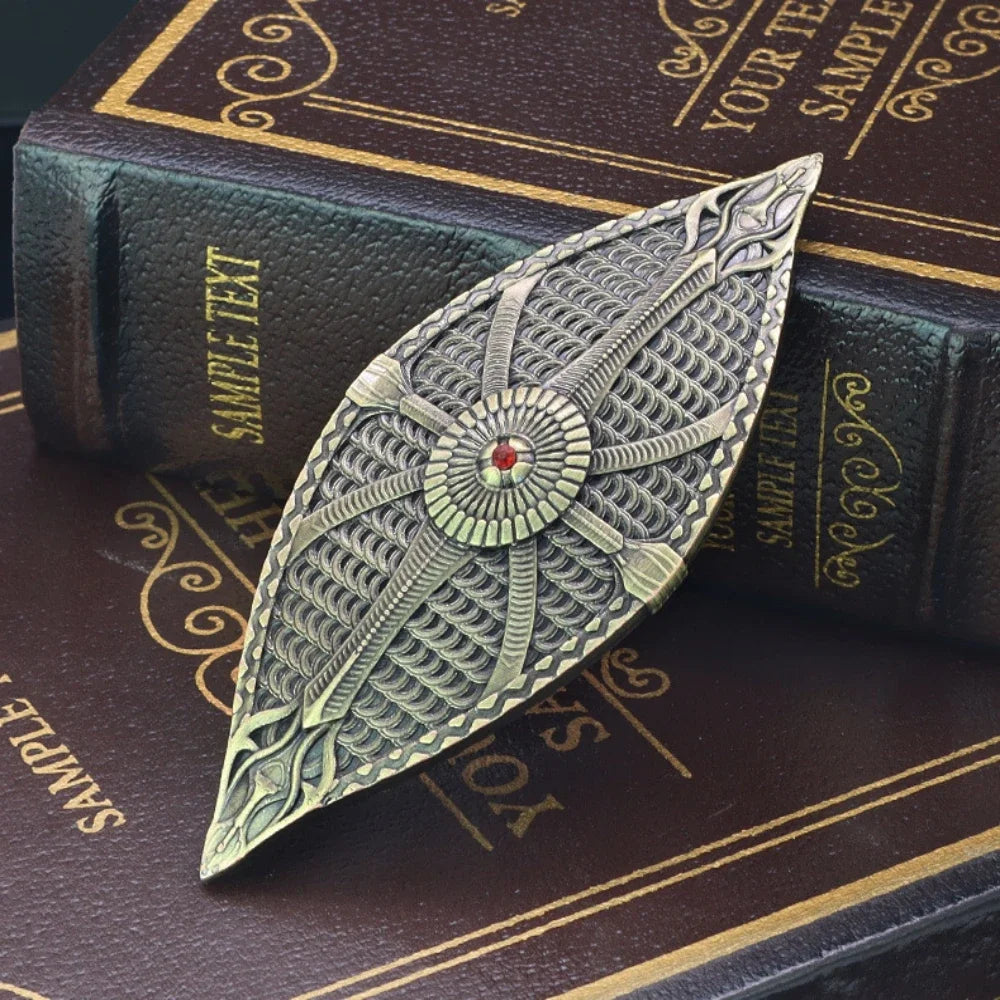 A detailed metal sword ornament with intricate feather patterns rests on a dark leather-bound book.