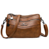 A brown leather compact square crossbody bag with gold hardware and double-deck zipper storage.