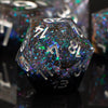 A close-up of a dark, iridescent resin polyhedral die with numbers visible on its faces.