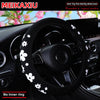 Black steering wheel cover with white floral pattern installed in a car interior.