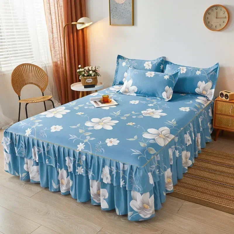 Jupe de lit à motifs floraux bleu clair couvrant un lit, dans une chambre lumineuse avec lumière naturelle.