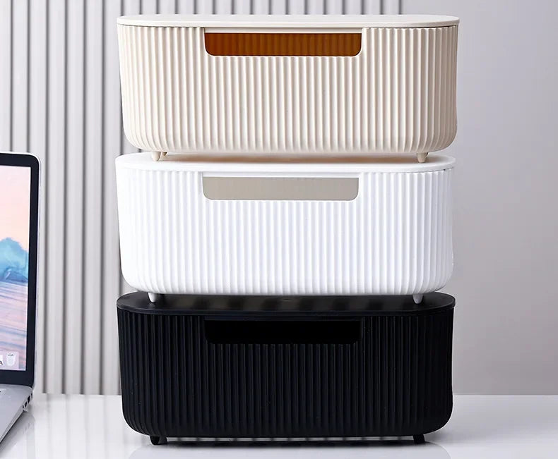 A stack of three white and black cable management boxes for organizing power strips and cords on a desk.