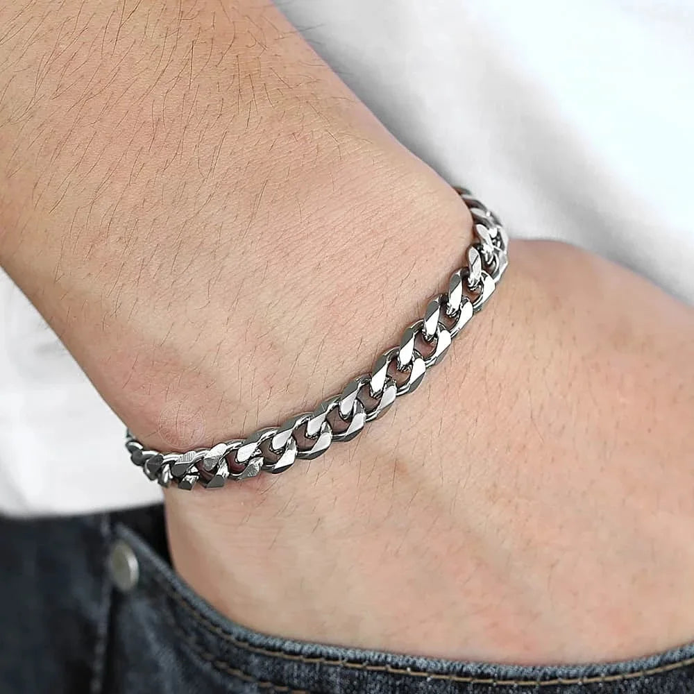 A close-up of a silver stainless steel Cuban link bracelet worn on a wrist.