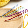 A collection of twenty large eye tapestry needles in various colors, including blue, yellow, green, and purple, resting on a 