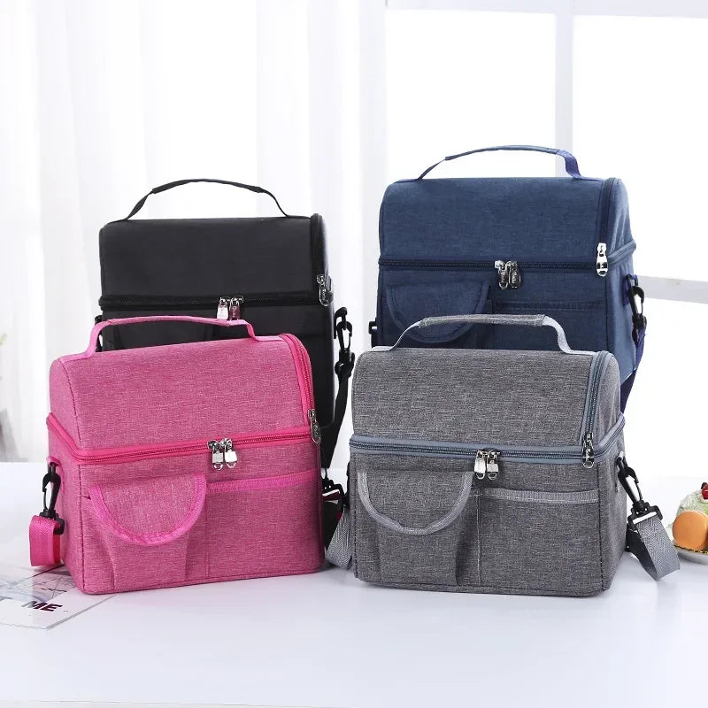 A collection of three insulated lunch bags in pink, navy blue, and gray are displayed on a white surface.