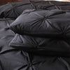 Black queen comfort bedding set featuring a comforter and pillowcases stacked on a dark surface.