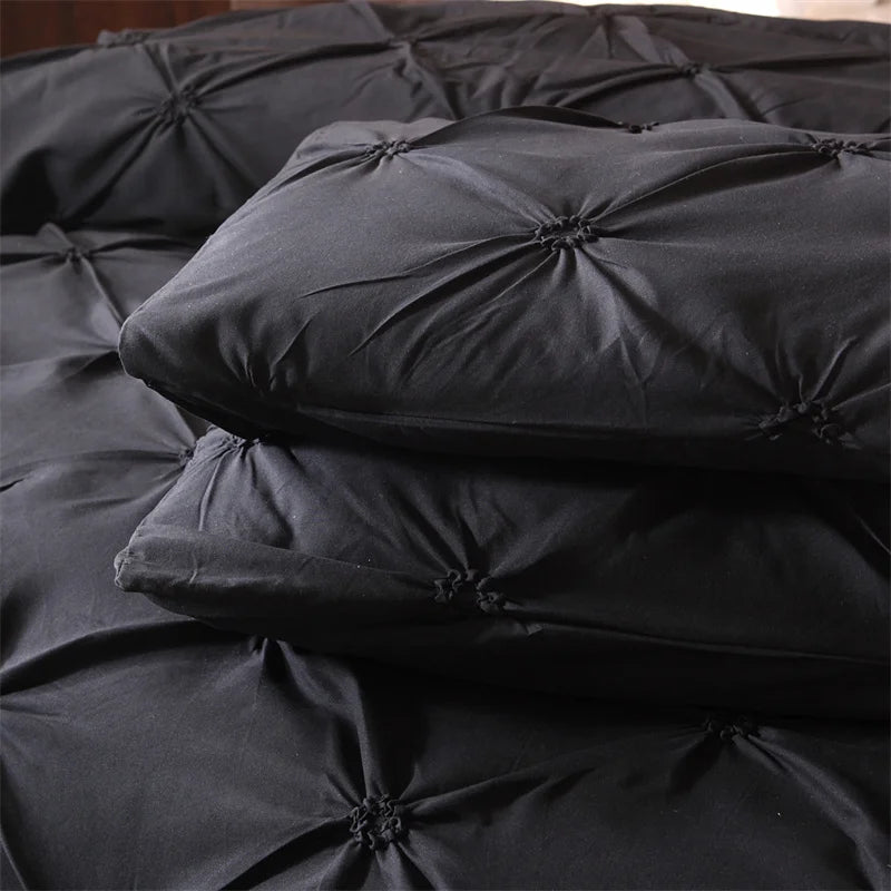 Black queen comfort bedding set featuring a comforter and pillowcases stacked on a dark surface.