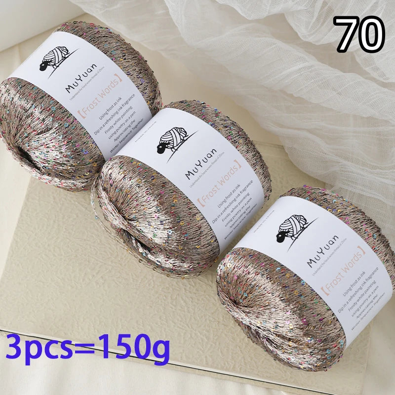 Three skeins of glitter yarn labeled MuYuan Frost Words are displayed on a light surface.