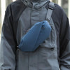 A man wearing a gray waterproof jacket has a navy blue running waist pack attached to his chest.