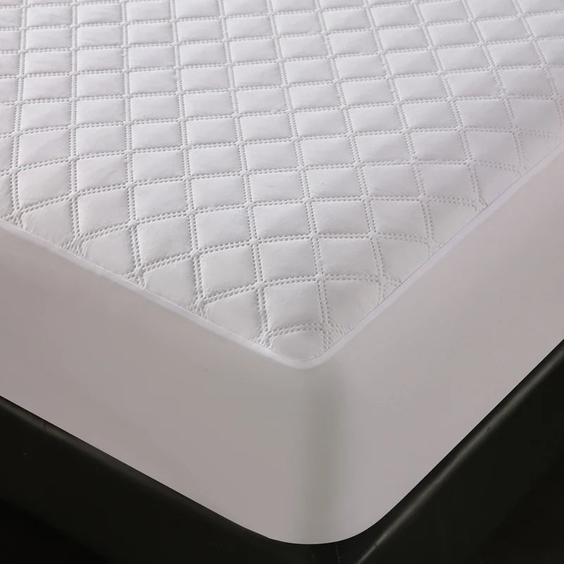 White quilted waterproof mattress protector with deep pockets shown on a black mattress.
