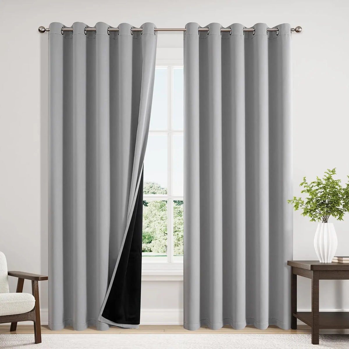 Gray insulated blackout curtain panels with grommet tops hanging in a window frame.