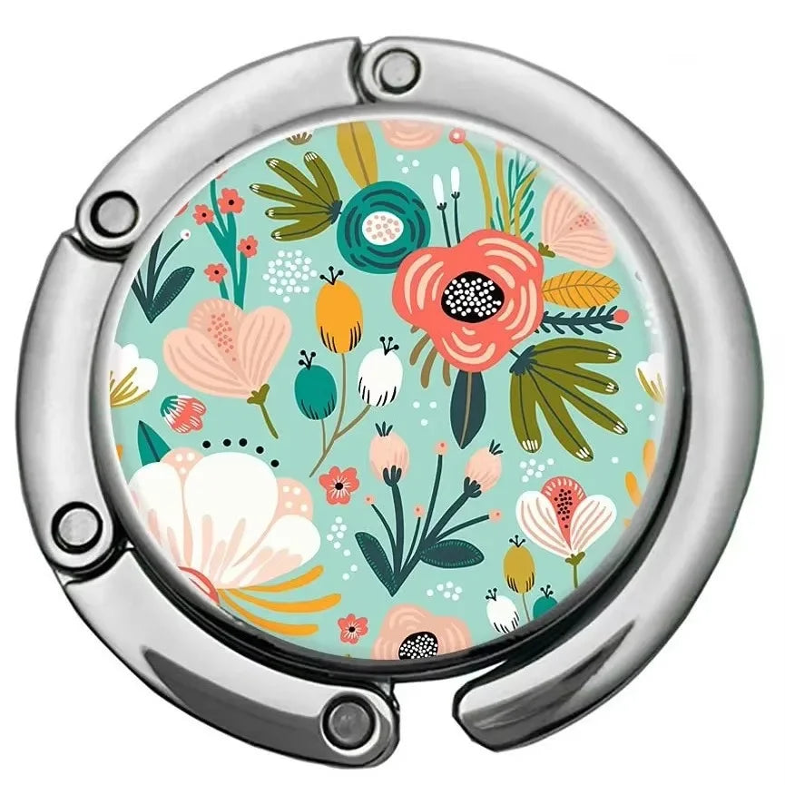 A silver bag hook with a circular, multi-pattern floral design featuring green, pink, and orange leaves.