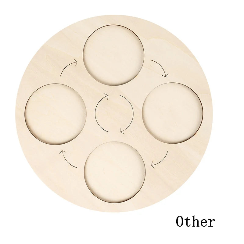 A light wooden board with five circular cutouts arranged in a cross pattern for a life cycle learning model.