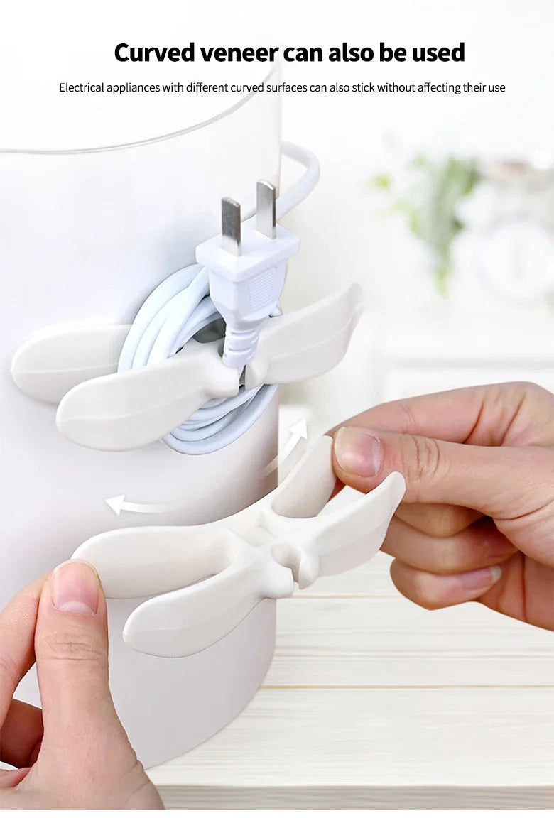 A hand is using a curved veneer to organize and secure electrical wires and plugs.