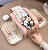 A pink waterproof PU leather cosmetic bag is open, displaying various makeup and skincare products.