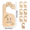 A set of wooden baby closet dividers used to organize clothing by size from newborn to 24 months.