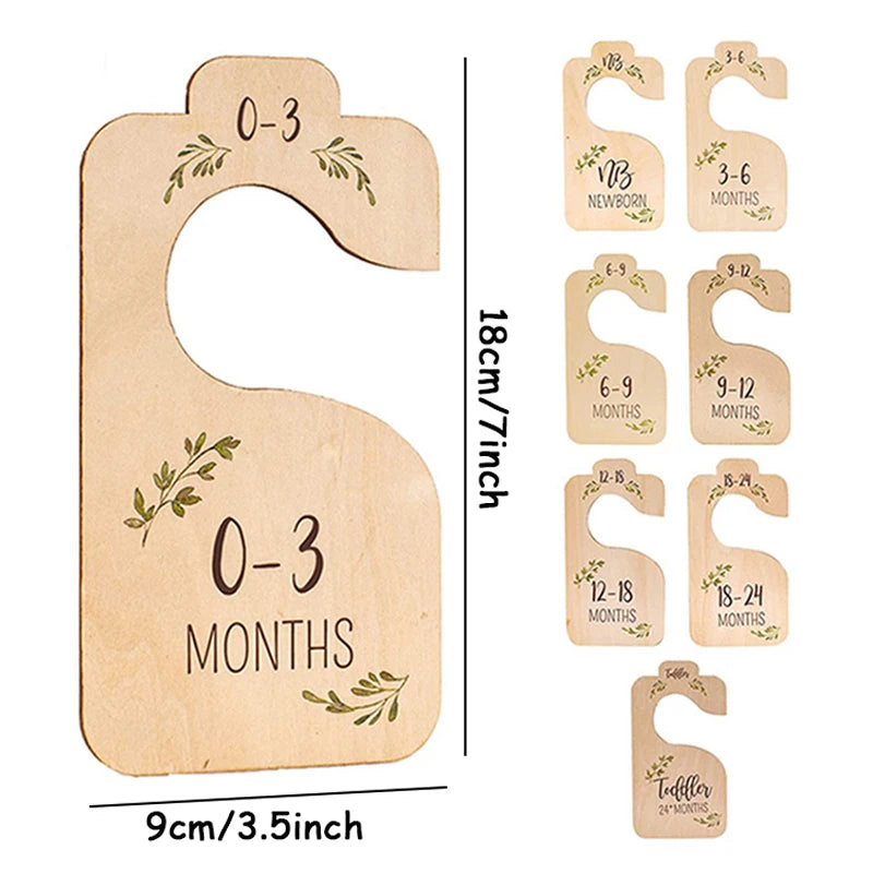 A set of wooden baby closet dividers used to organize clothing by size from newborn to 24 months.