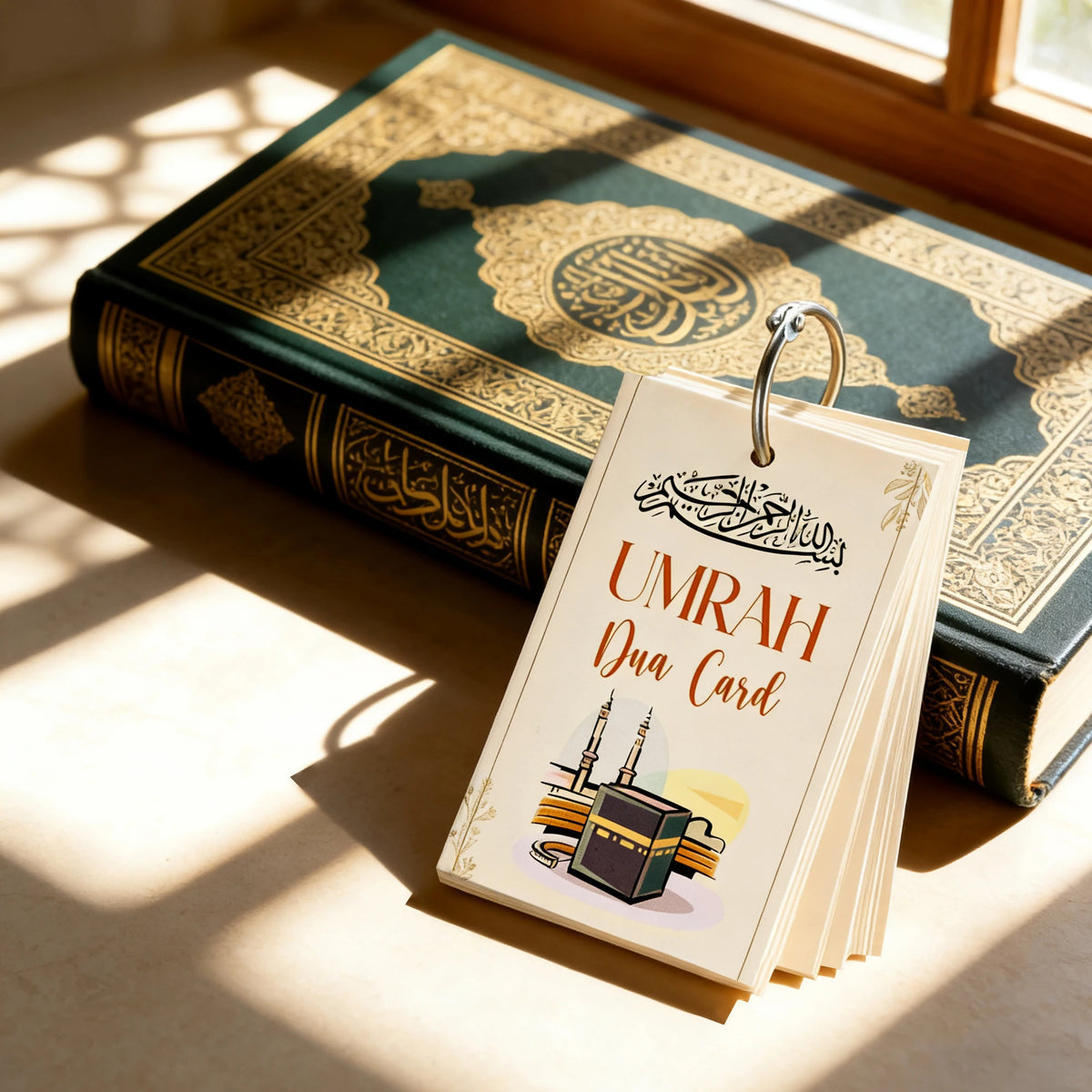 A set of portable Islamic Dua cards resting on a green-covered book near a window.