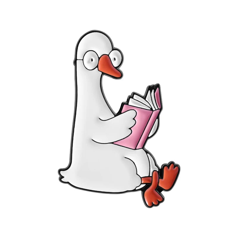 A white duck wearing glasses is sitting and reading a pink book enamel pin.