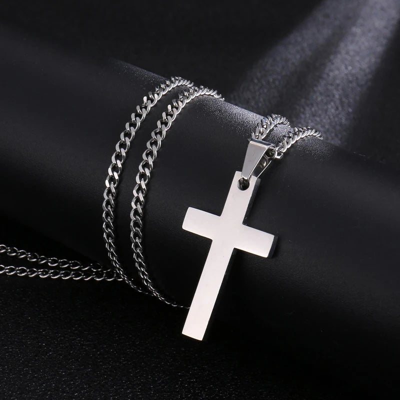 A silver stainless steel cross pendant necklace is displayed against a dark background.