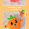 Two plush dolls shaped like a strawberry and a carrot resting on a white fuzzy surface.
