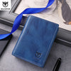 A dark blue genuine leather men's bifold wallet with stitching and a blue ribbon, shown on a gray surface.