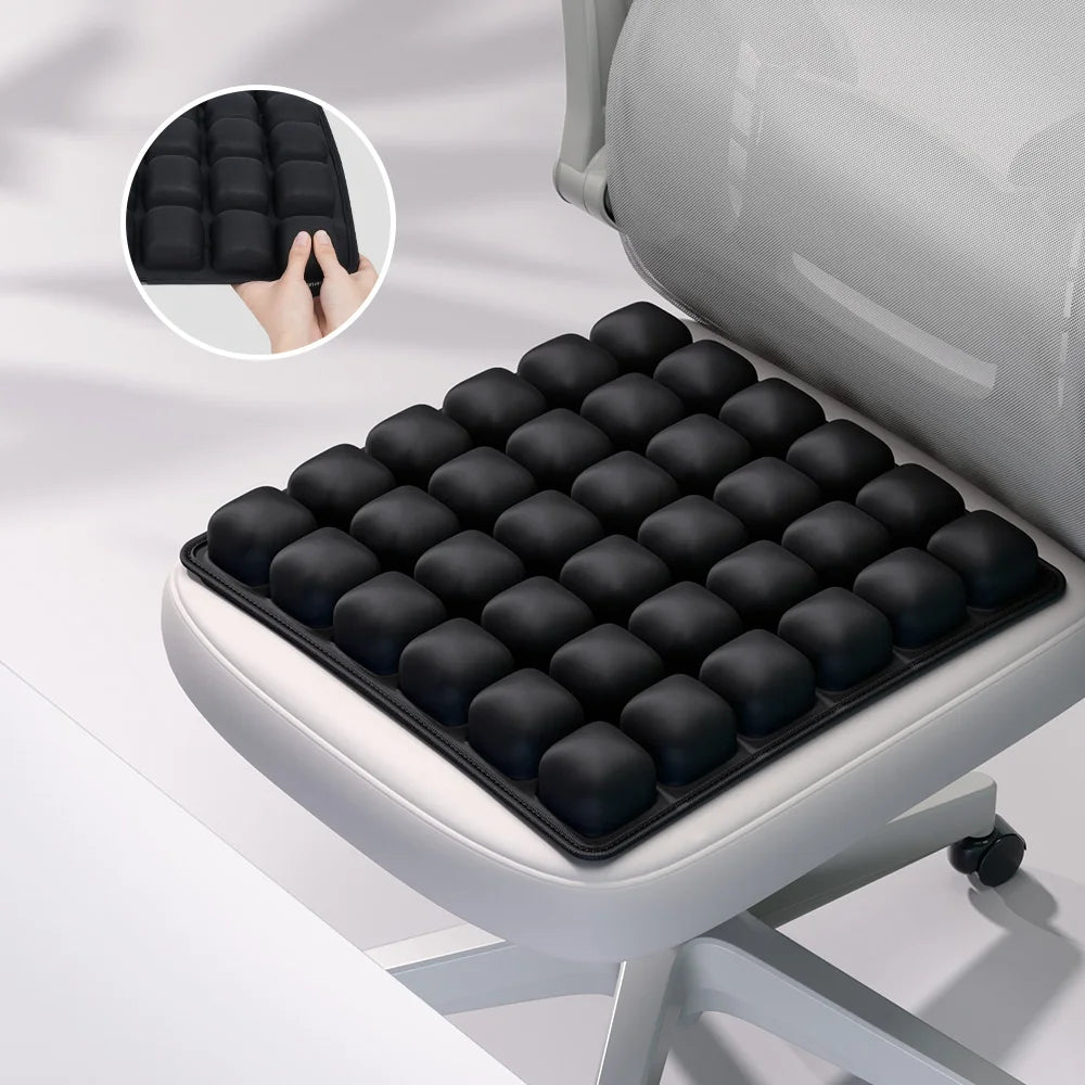 A black adjustable press-to-inflate seat cushion with a hand demonstrating its use, shown in an office chair context.
