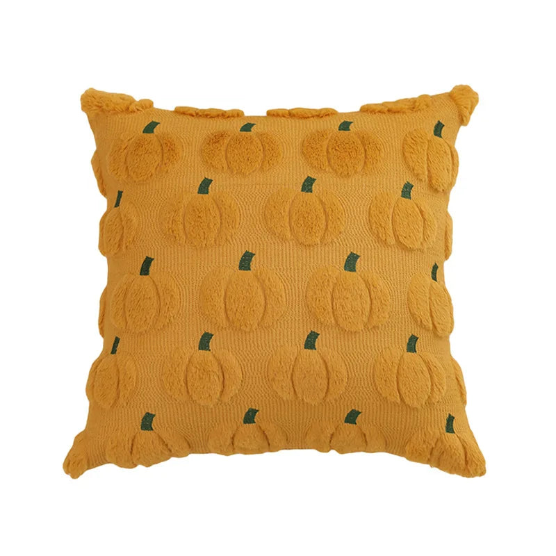 A square plush throw pillow covered in an orange fabric featuring a repeating pattern of small green pumpkins.