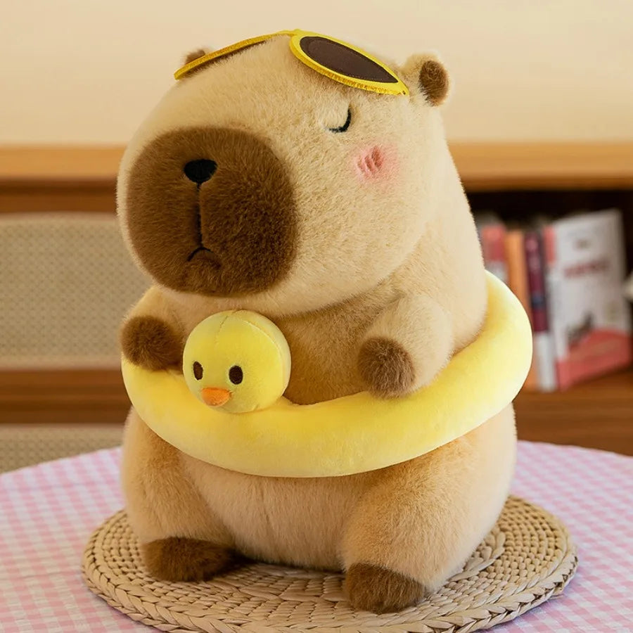 A fluffy brown capybara plush toy wearing a yellow swim ring shaped like a duck.