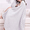 A white striped bath towel is draped over a woman sitting on a sofa.