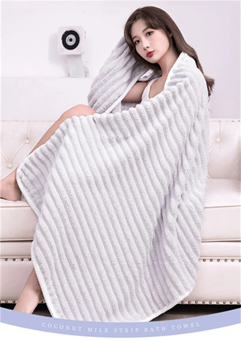 A white striped bath towel is draped over a woman sitting on a sofa.
