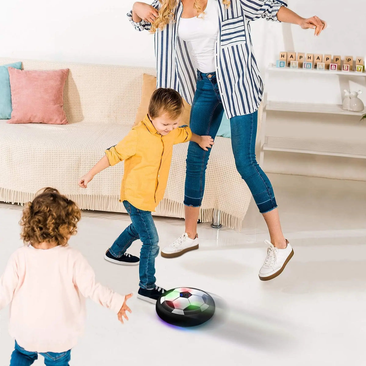 A woman is helping a young boy kick a soccer ball that is levitating above the floor.