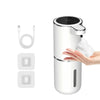 A white touchless automatic soap dispenser with a black top, shown next to its charging cable and replacement parts.