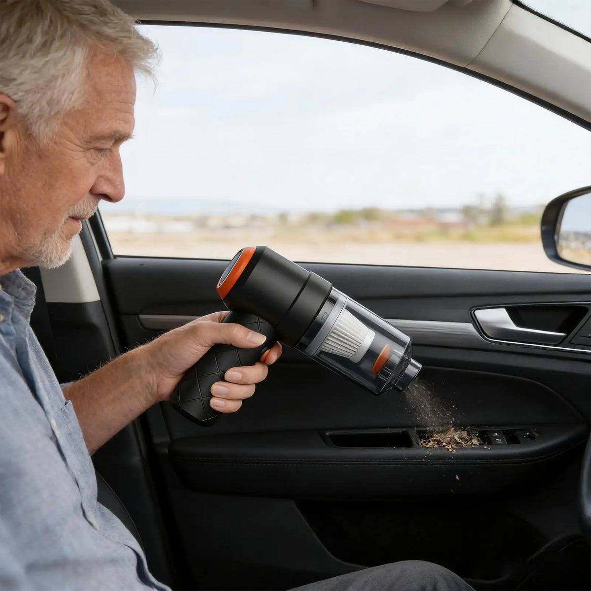 A man is using a cordless handheld car vacuum cleaner to clean the interior of a car.