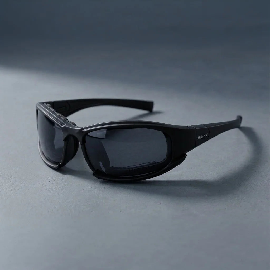 Un par de gafas tácticas polarizadas negras con lente oscuro sobre una superficie gris.