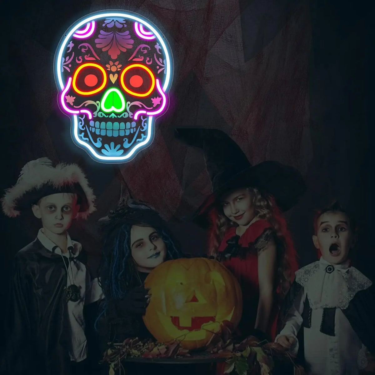 A group of children posing with a glowing skull-shaped LED neon light and a carved pumpkin.